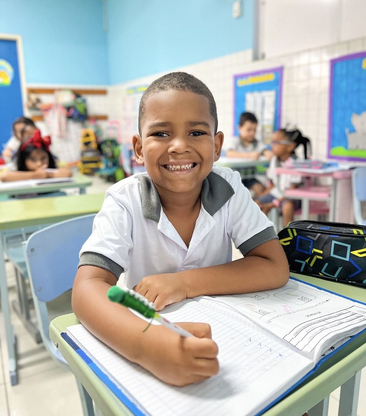 Aluno sorridente estudando em sala de aula