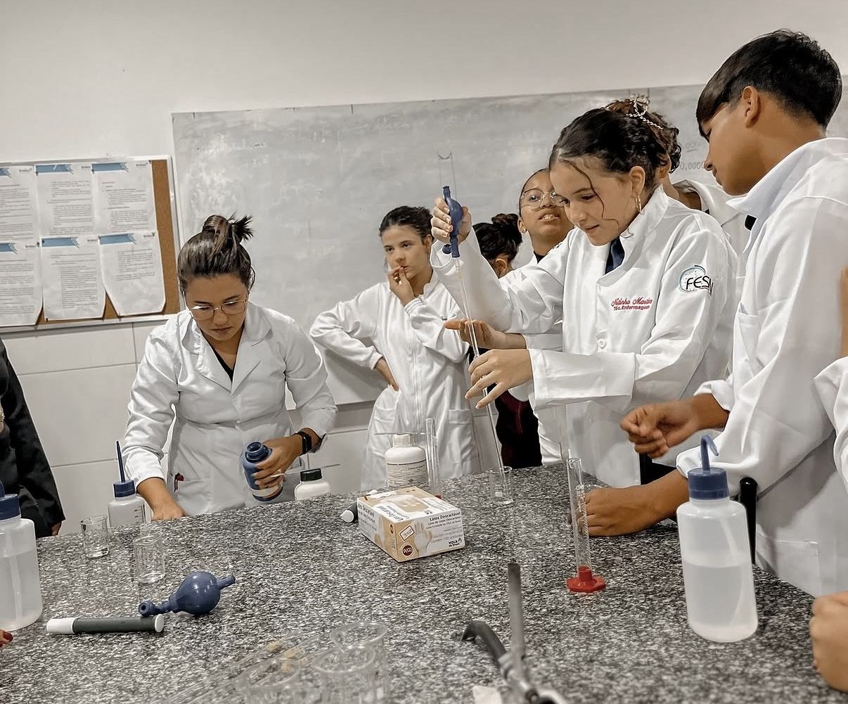 Grupo de alunos de jaleco em aula no laboratório de ciências